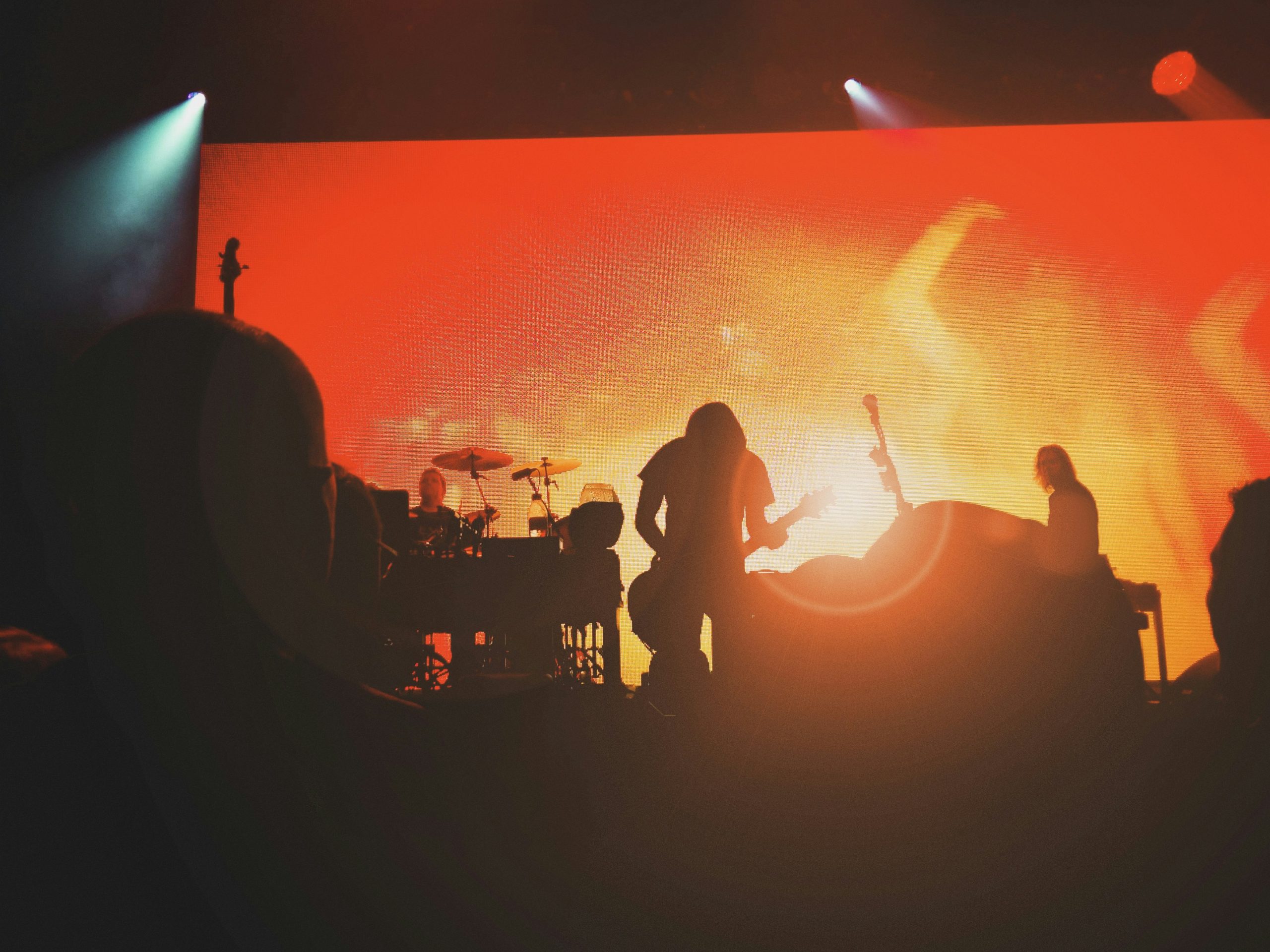 Band performing on stage in silhouette against an orange screen